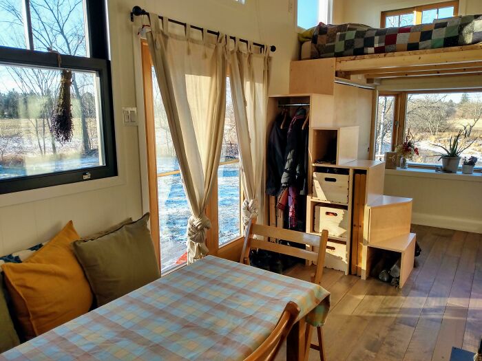 Wooden glass doors with curtains in a cozy tiny house design featuring natural light and warm interior tones.