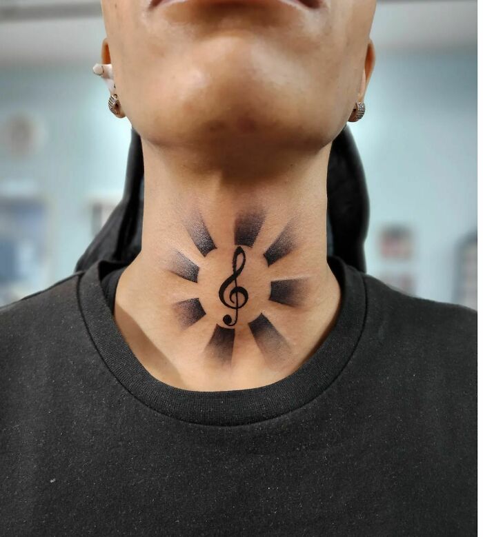 Neck tattoo featuring a bold music note design with surrounding shaded patterns.