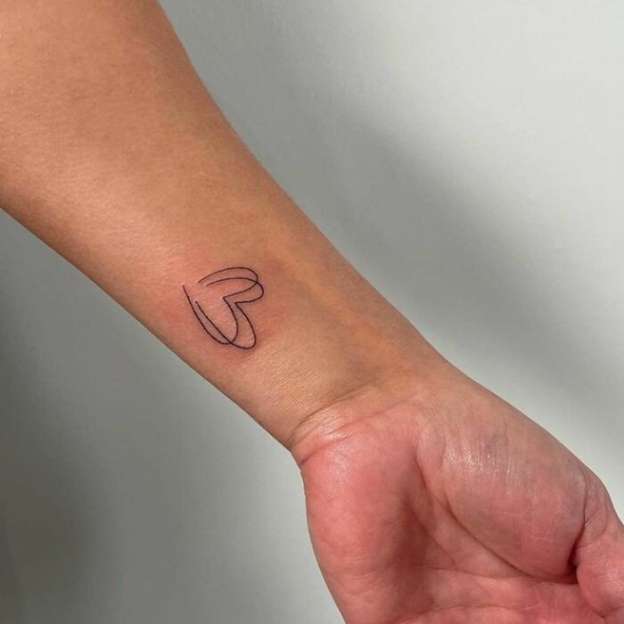 Minimalist heart tattoo on a wrist, showcasing a unique design idea.