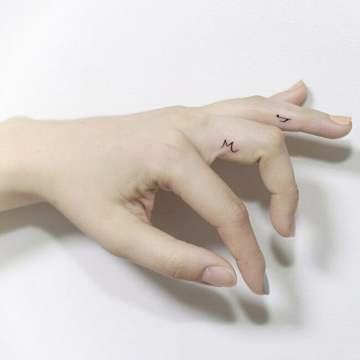 Delicate music tattoos on fingers, minimalist design on light skin.