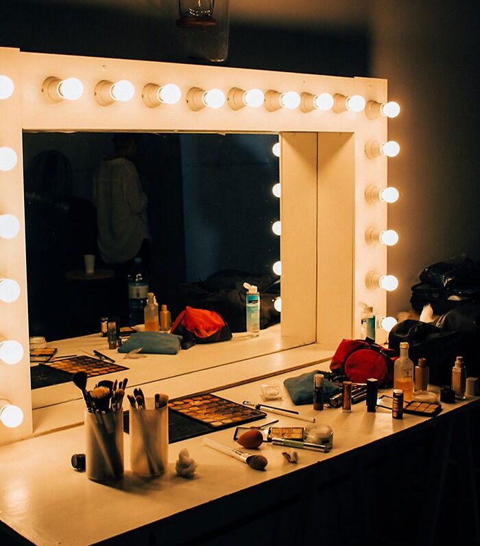 Fancy mirror with lights surrounded by makeup, inspired by fun hobbies in beauty and styling.