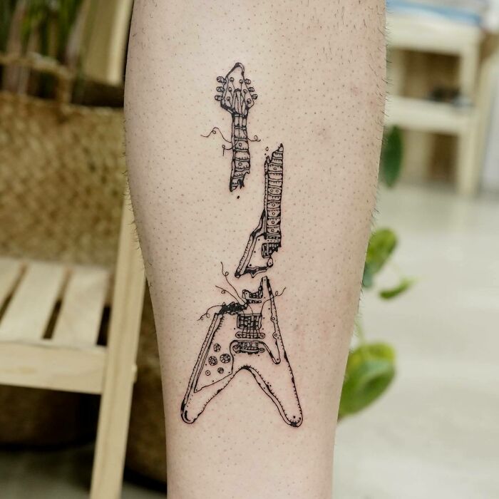 Tattoo of a disassembled electric guitar on a person's calf, showcasing unique music-themed ink art.