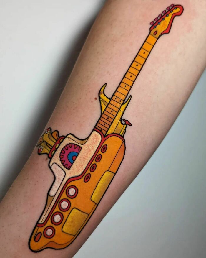 Colorful guitar tattoo on forearm, showcasing music tattoo art with vibrant details and unique design.