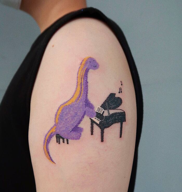 Tattoo of a dinosaur playing a piano, artistically representing music tattoos with creativity and charm.