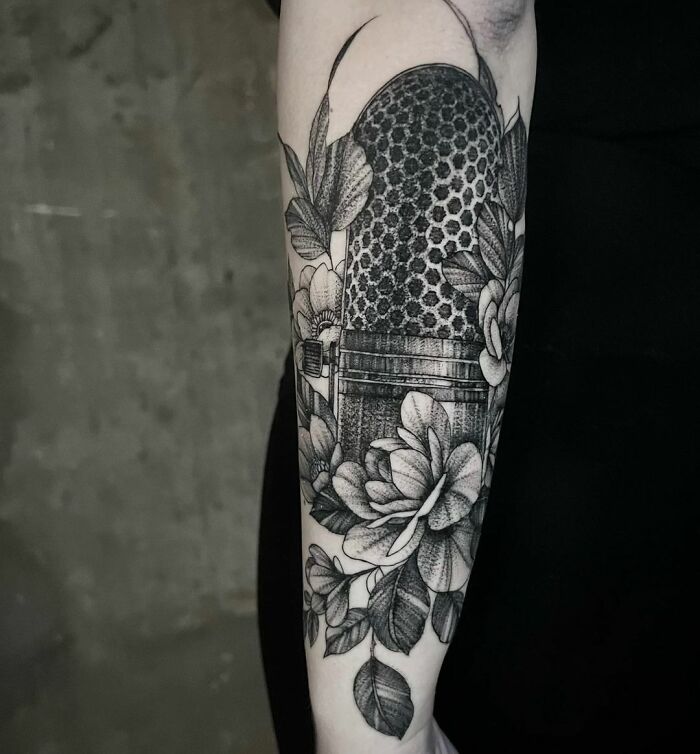 Microphone and floral themed music tattoo on forearm with intricate details.