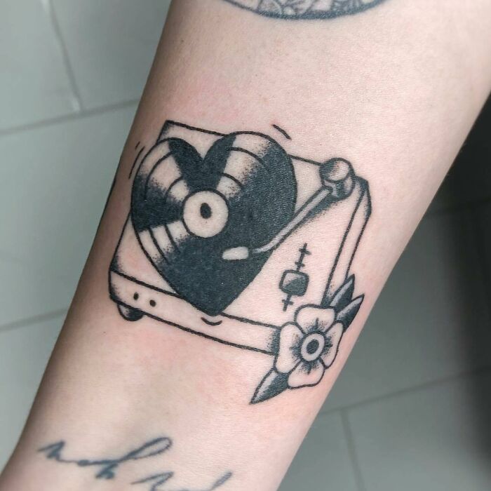 Tattoo featuring a record player with a heart-shaped vinyl, highlighting unique music tattoos.