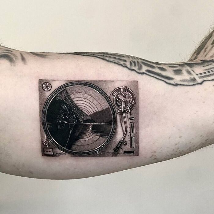 Turntable tattoo on arm, showcasing detailed music-themed ink art.