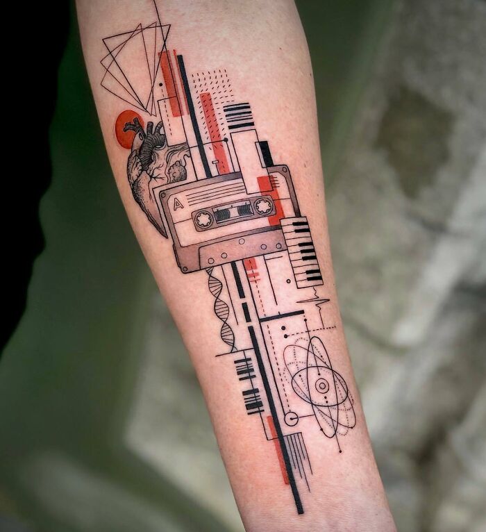 Geometric music tattoo with cassette and piano keys on forearm, blending art and music elements creatively.