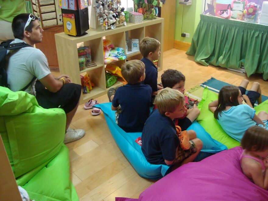 Man sitting with multiple children in a play room 