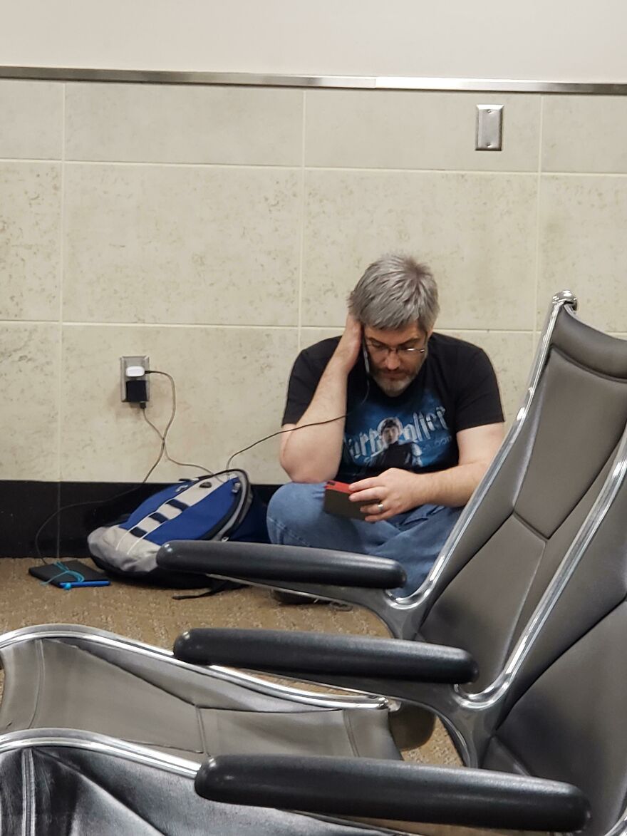 Man sitting on the ground next to a plugin socket talking on the phone 