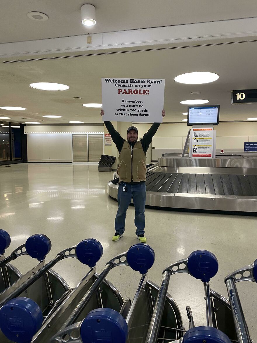 Man holding funny airport welcoming sign 