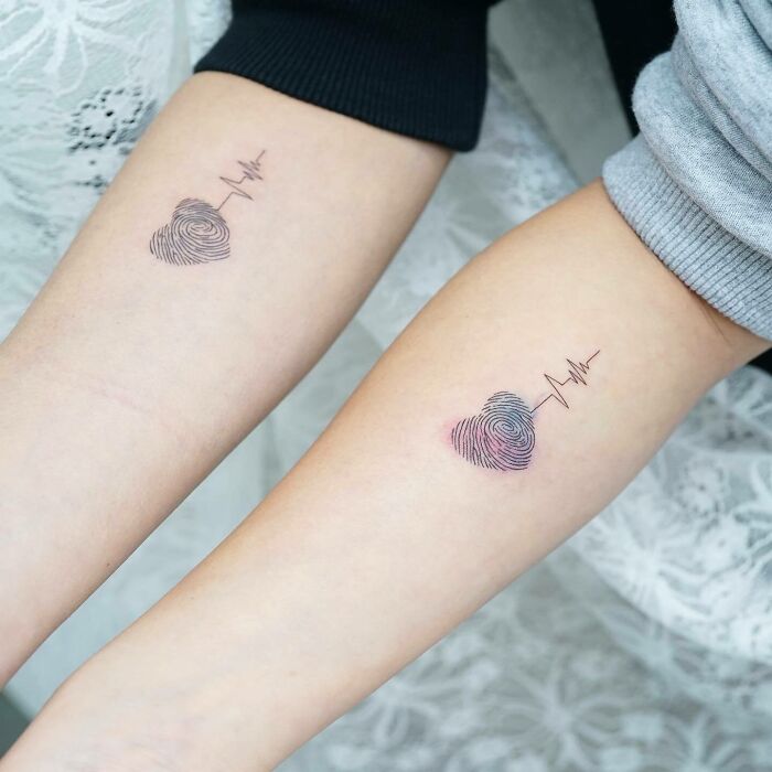 Matching family tattoos with heart-shaped fingerprint design symbolizing bonds.