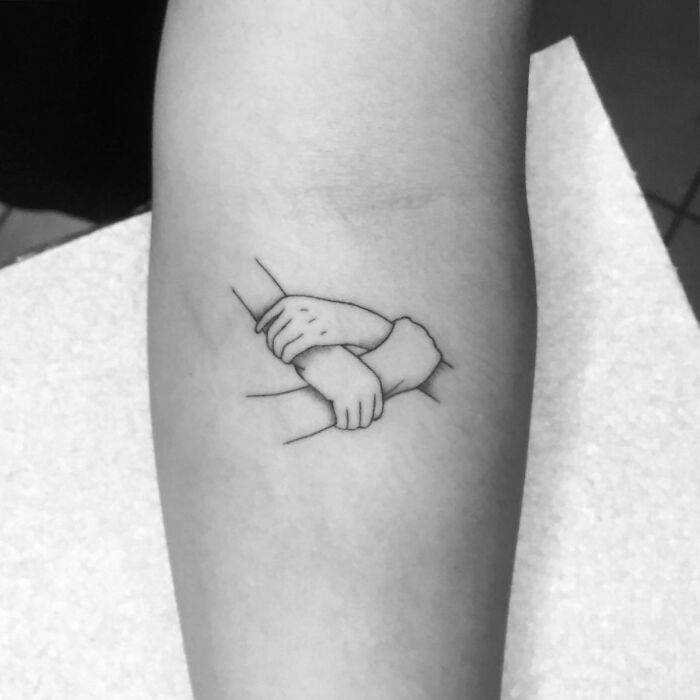Minimalist family tattoo depicting two hands clasped together, symbolizing unbreakable bonds.