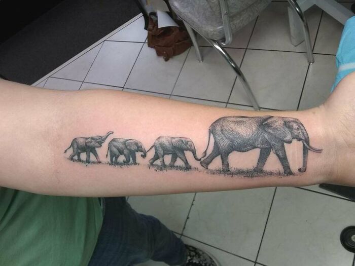 Elephant family tattoo symbolizing unbreakable bonds on forearm.