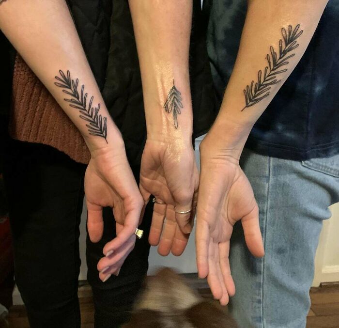 Three forearms displaying matching family tattoos symbolizing unbreakable bonds.