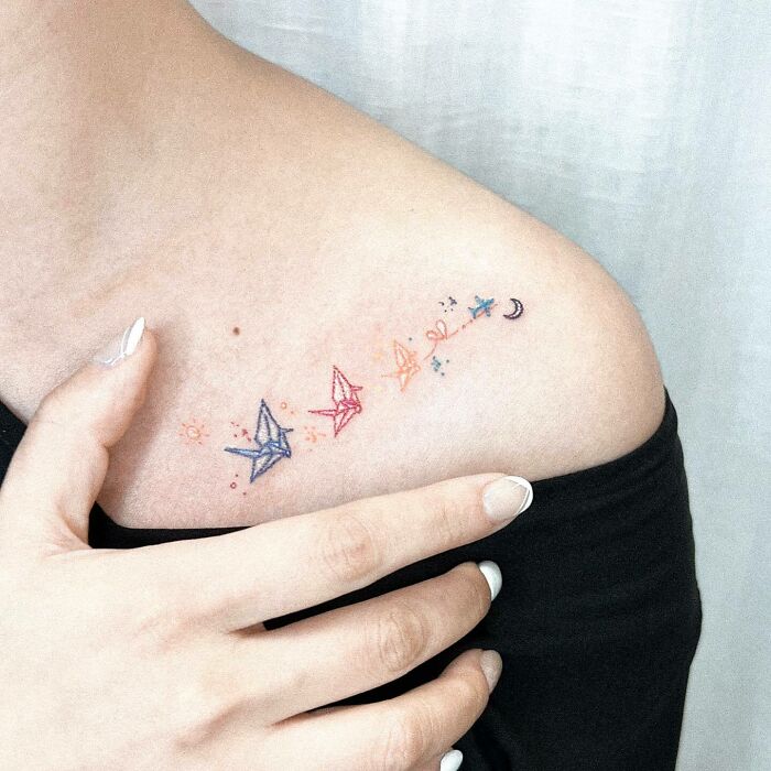 Colorful origami bird tattoo symbolizing family bonds on shoulder.
