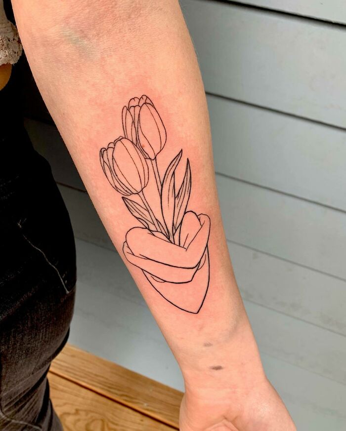 Tulip tattoo on forearm symbolizing family bonds, featuring two flowers held by a heart-shaped hand.