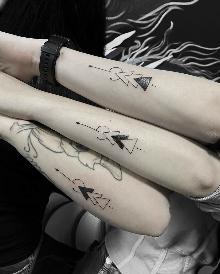 Matching arrow tattoos symbolizing family bonds on three forearms.