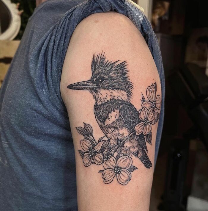 Nature tattoo featuring a detailed bird and flowers on a person's upper arm.