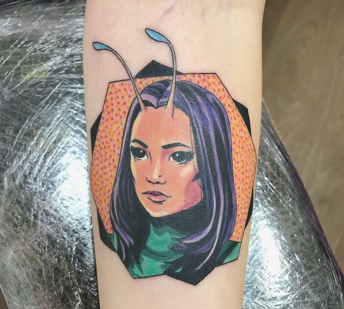 Marvel tattoo of a character with antennas and purple hair on a forearm, showcasing vibrant colors and comic book style.