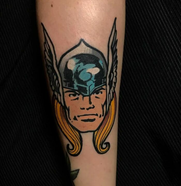 Thor tattoo on forearm, featuring classic Marvel comic style with helmet and wings, showcasing cool Marvel tattoo art.