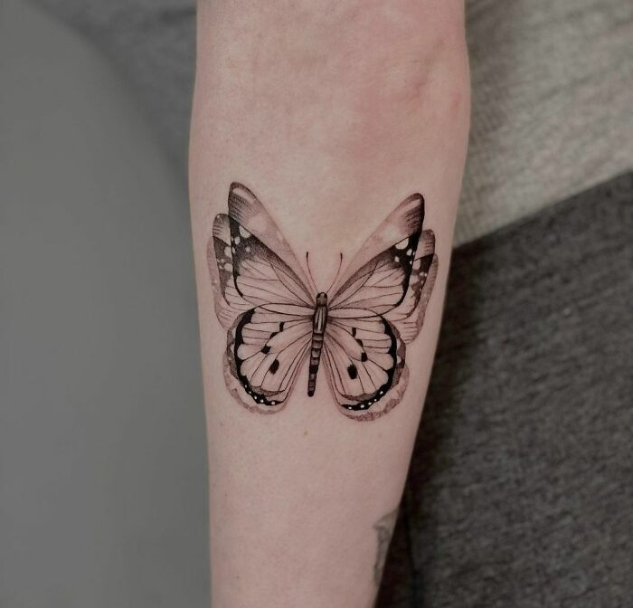 Butterfly optical illusion tattoo on forearm, showcasing intricate details and realistic shading.