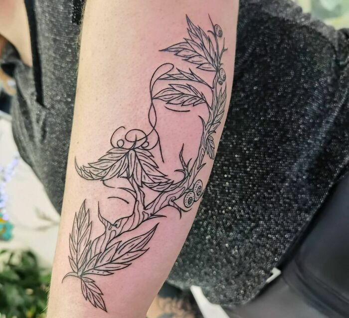 Optical illusion tattoo on arm, featuring intricate leaves and abstract design.