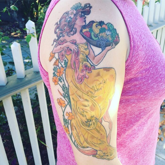 Watercolor tattoo of a goddess with food basket on arm, showcasing food tattoo inspiration.