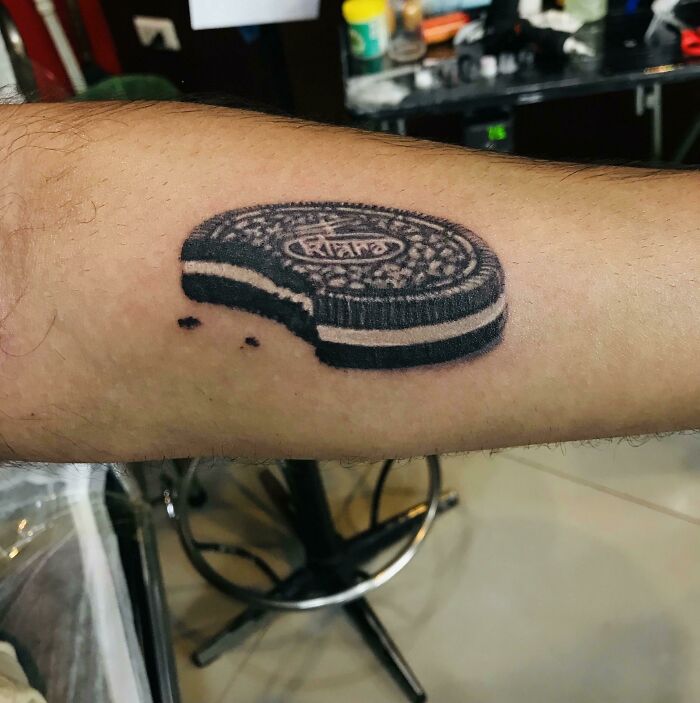 Oreo cookie watercolor tattoo on arm, showcasing creative food-themed ink-spiration.