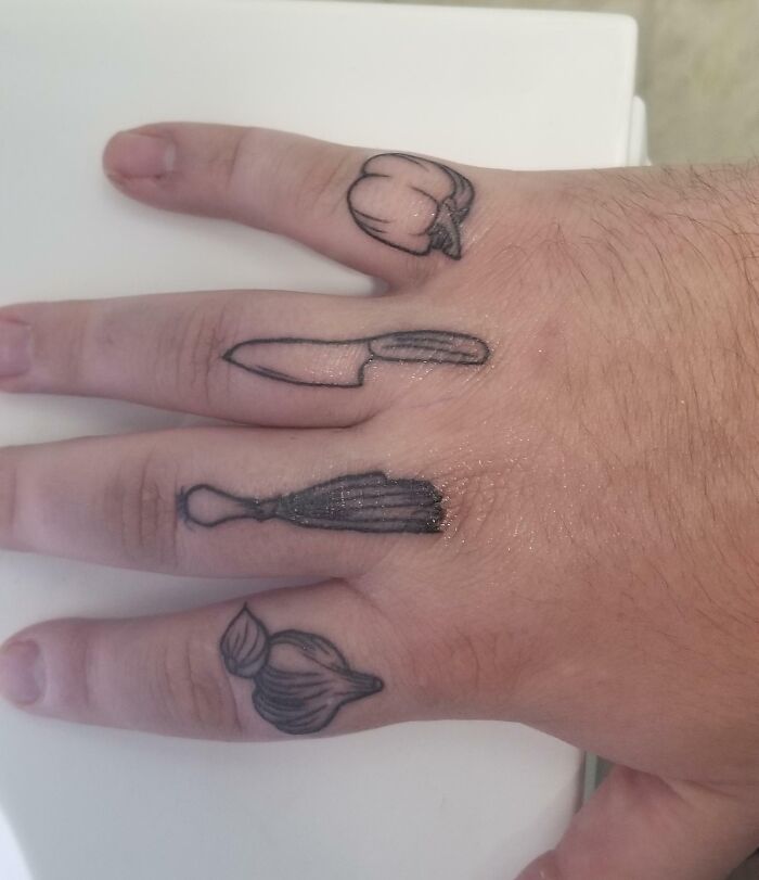 Food tattoos on fingers featuring paprika, knife, leek, and garlic designs.