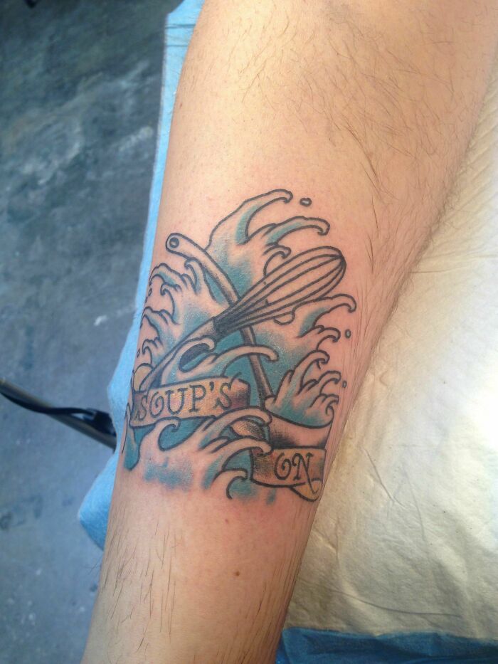 Food tattoo featuring soup waves and a whisk, with the words "Soup's On" on an arm.