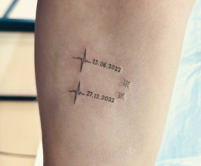 Minimalist mom tattoo featuring two heartbeat lines with dates, symbolizing the mother-child bond.