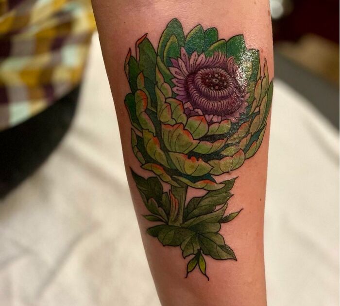 Food tattoo of a colorful artichoke design inked on a person's forearm.