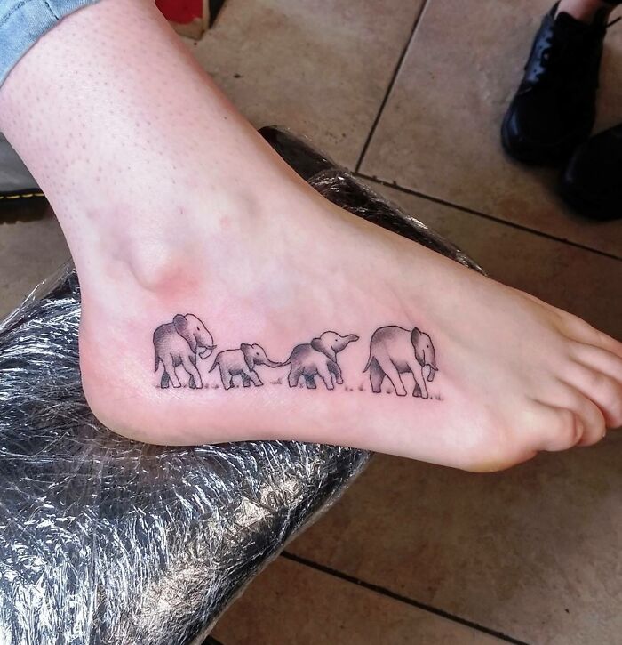 Elephant family tattoo on foot symbolizing the mother-child bond.