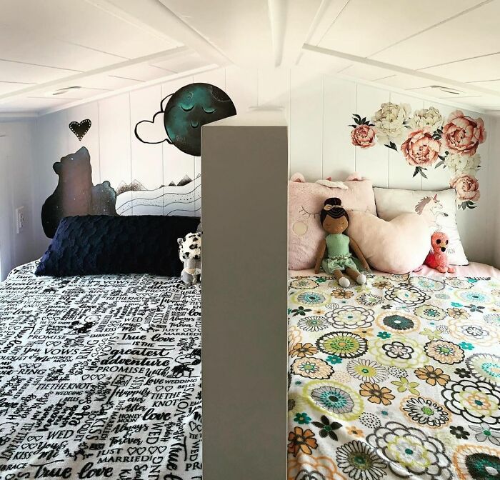 Cozy tiny house beds separated by a partition, featuring playful wall art and colorful bedding in a compact space.