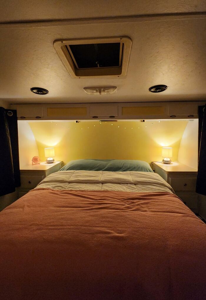 Cozy tiny house bedroom with a bed featuring an orange blanket and warm lighting creating a relaxing atmosphere.