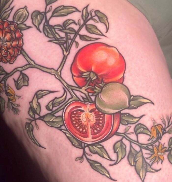 Food tattoo of tomatoes and leaves, vividly inked on skin.