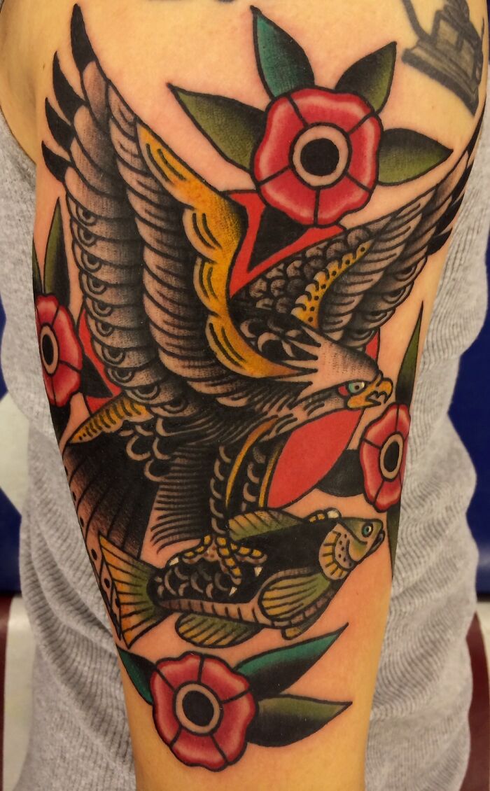 American traditional tattoo featuring an eagle and roses in bold colors on an arm.