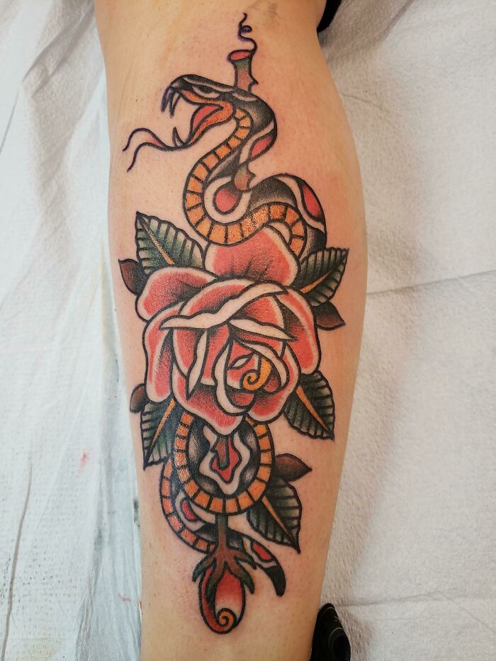 American traditional tattoo showcasing a coiled snake and rose design on the forearm.