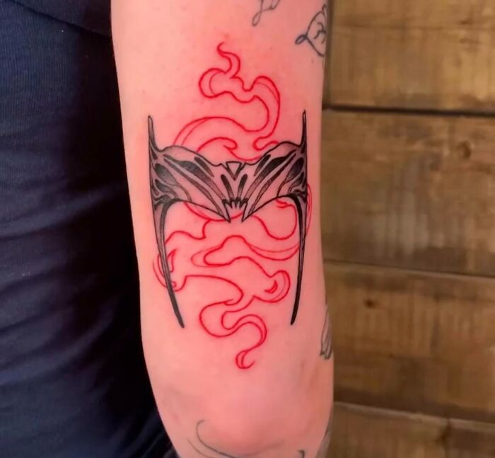 Marvel tattoo featuring a stylized black and red design on an arm.