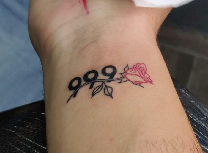 Wrist tattoo with number 999 and a pink rose design.