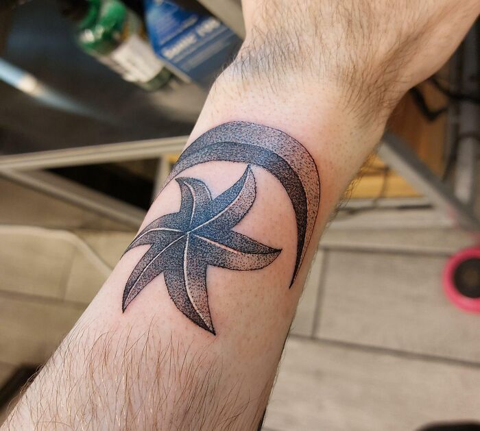 Stylized star and crescent wrist tattoo design in black and grey.