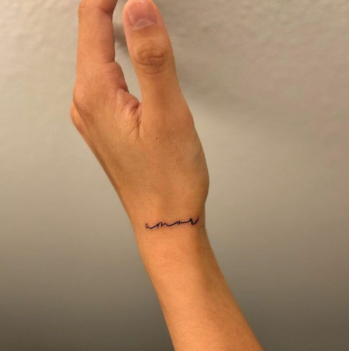 Delicate wrist tattoo with "amore" in cursive, showcasing timeless accessory appeal.