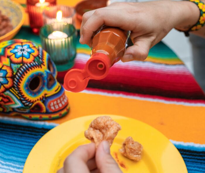 Person putting some hot sauce on the snack 