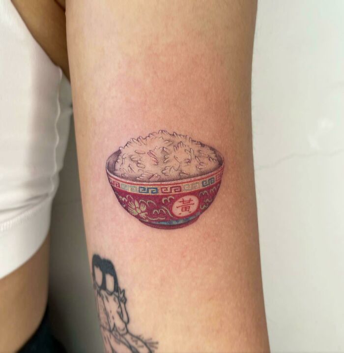 Tattoo of a colorful rice bowl on an arm, showcasing delicious food ink design.
