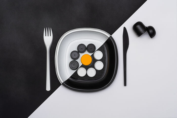 Black and white contrasting plate with black and white caps and an orange center, illustrating global problems on a plate concept.