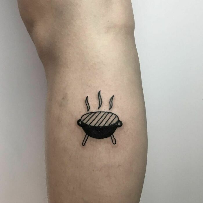 Tattoo of a steaming grill, a small food-themed design on the arm.