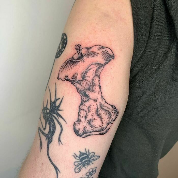 Food tattoo of a detailed apple core inked on an arm, showcasing creative and unique artwork.
