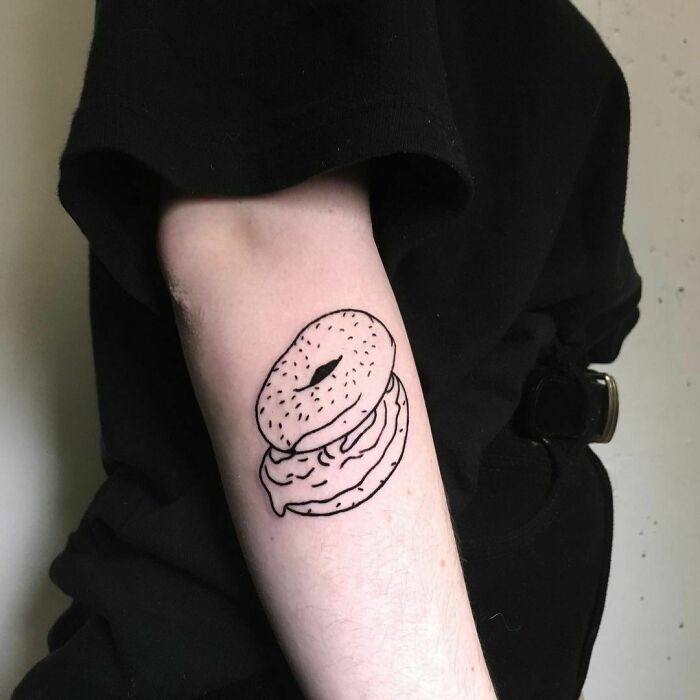 Black and white tattoo of a bagel with cream, showcasing food tattoo inspiration.