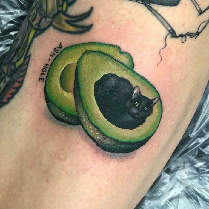 Watercolor tattoo of a cat inside an avocado, blending food art with playful ink-spiration.